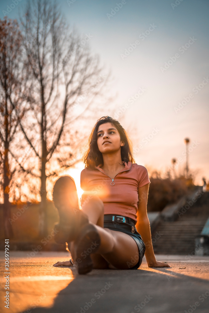 Lifestyle, a young brunette with pink shirt on a sunset sitting