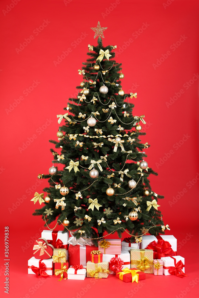 Christmas fir tree with ornaments and gift boxes on red background Christmas fir tree with ornaments and gift boxes on red background
