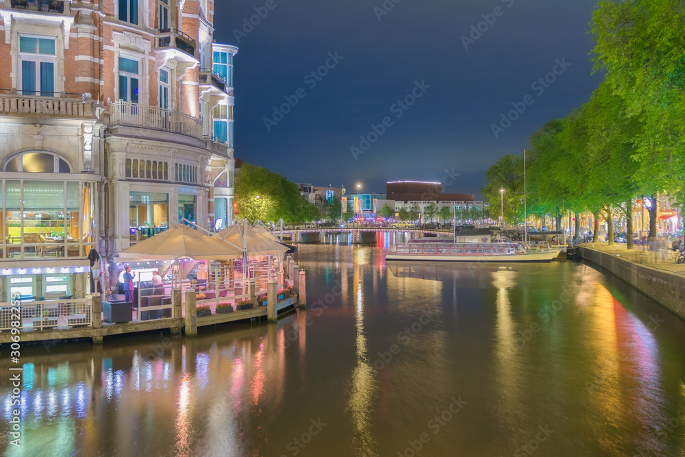Night view of Amsterdam city, reflecting in the water. The Netherlands.
