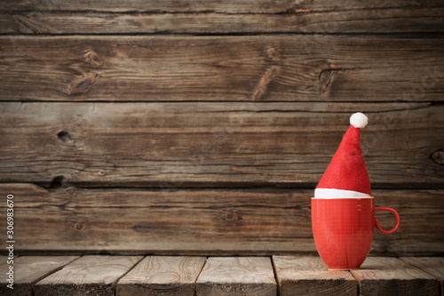 funny red cup in santa hat on old dark wooden background