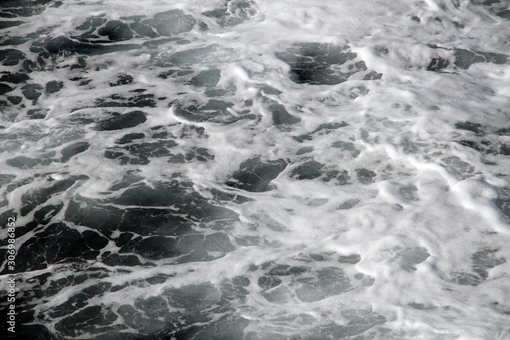 Weisser Schaum und Wellen auf der Wasseroberfläche im Meer. Gischt am Ozean bei einer Fahrt mit dem Schiff. Wasser in Bewegung. Flut