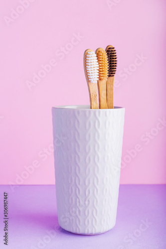 Natural bamboo toothbrushes in glass on color pink background. Biodegradable natural bamboo toothbrush. Eco friendly, Zero waste, Dental care, Plastic free concept