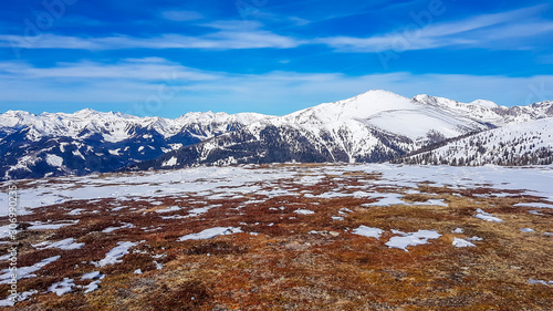 A panoramic view on snow caped mountains in Bad Kleinkirchheim, Austria. Snow is slowly melting in slower parts of the mountains. The barren ground has golden colour. Warm feeling. Spring is coming.