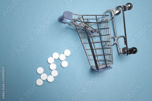 Pills / Shopping cart with sign dollaron a blue background /Close-up / Concept of healthcare, online shopping, high cost of medicines / Copy space for text