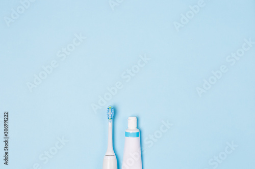 Tooth paste in tube and tooth brush on light blue background. Copy space. 