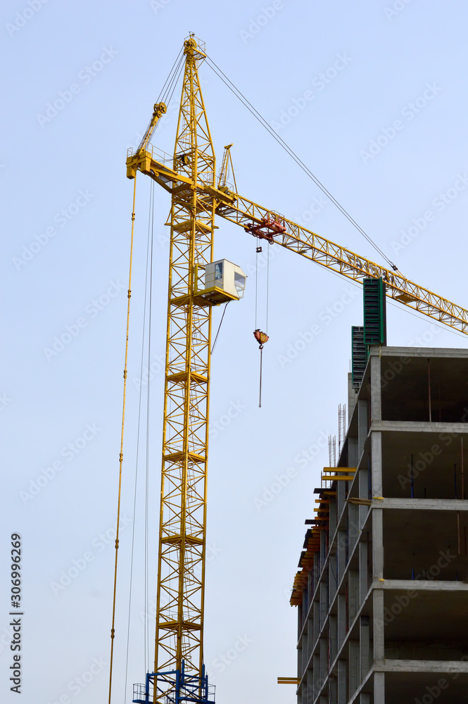 Construction crane at work, unfinished house. The property.