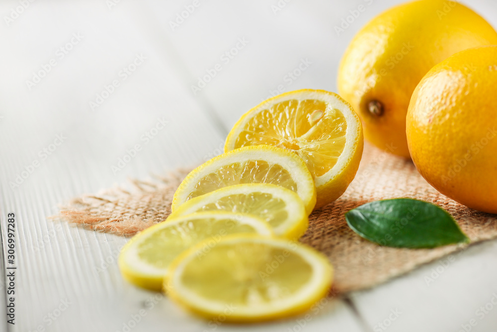 Cut slices of lemons on white table side view with old knife and green leaves. Cut slices of lemons on white table side view with old knife and green leaves.