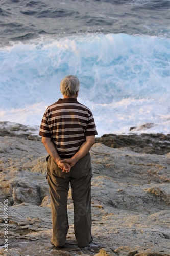 loneley sad senior man in grief watching the sea with waves photo