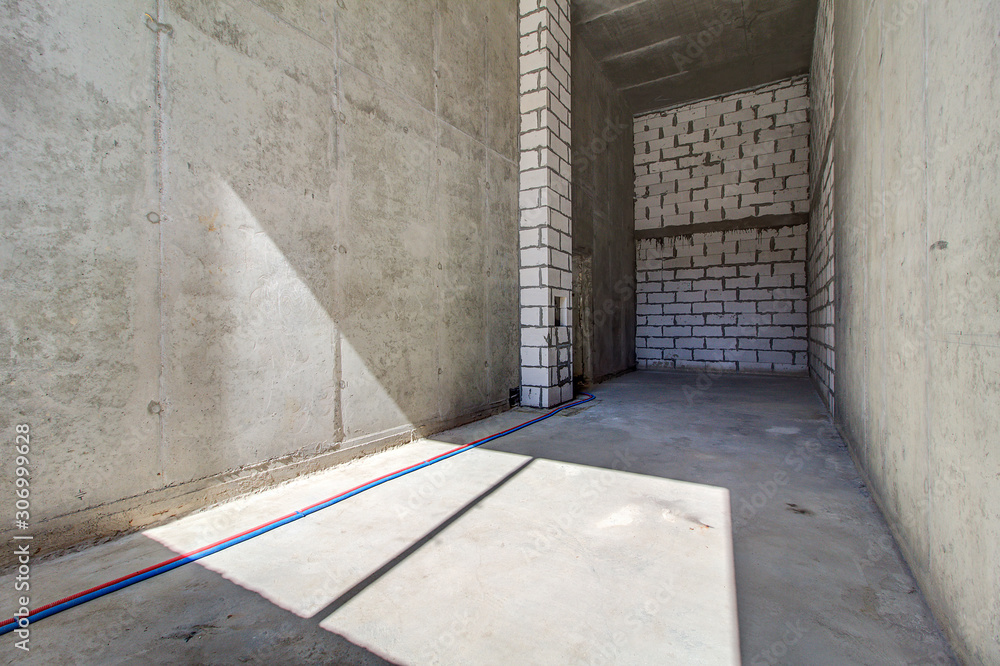 Monolithic brick basement wall. heating pipes lie on floor. New empty
