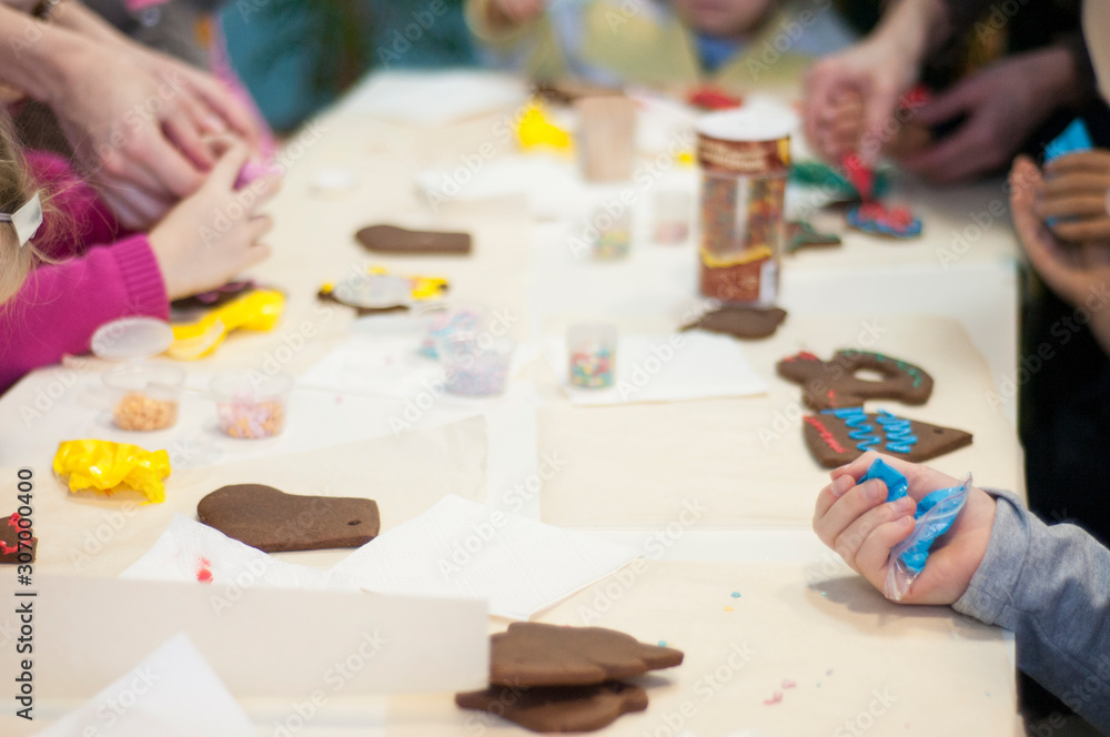 Children decorating Christmas cookies. Child’s hands and cookies covered with colored glaze. Homemade sweets. Cooking with children. Children decorating Christmas cookies. Child’s hands and cookies covered with colored glaze. Homemade sweets. Cooking with children.