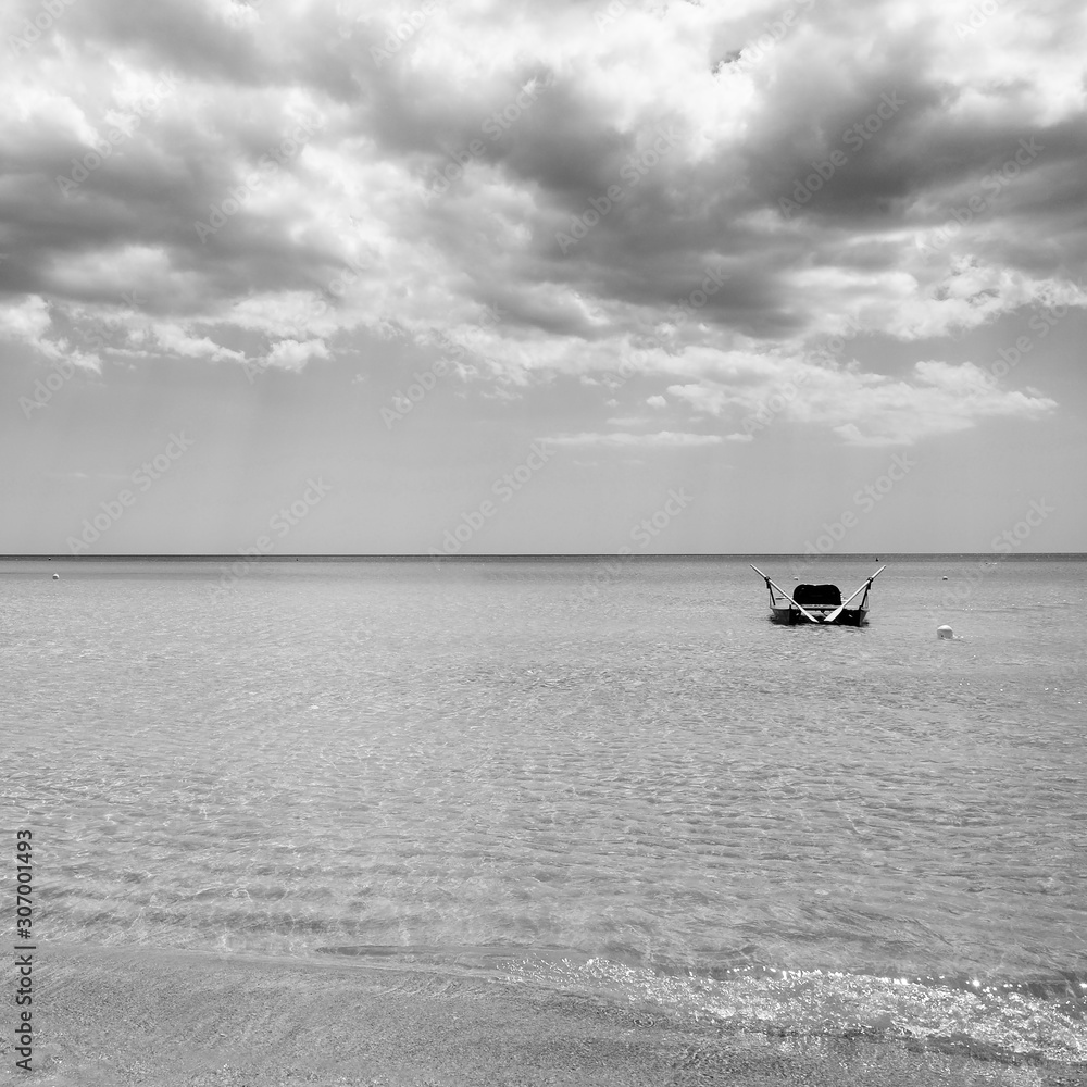 Fototapeta premium Rescue rowing boat on the sea against a cloudy and sunny sky. Beautiful view. Crystal clear water. Paradise beach.