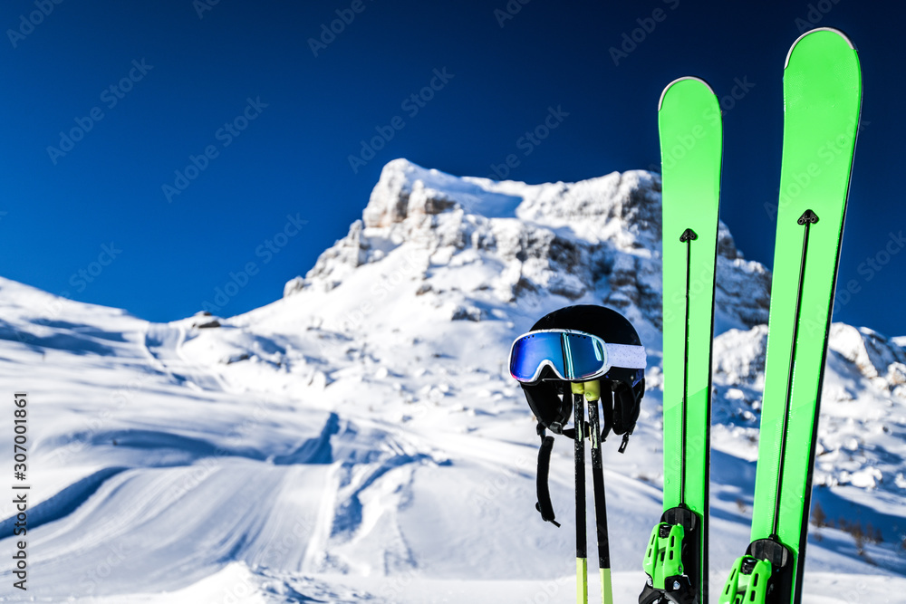 Skis in snow, mountains and ski concept equipments in sunny winter day. Fresh or new groomed slope at best piste resort. - obrazy, fototapety, plakaty 