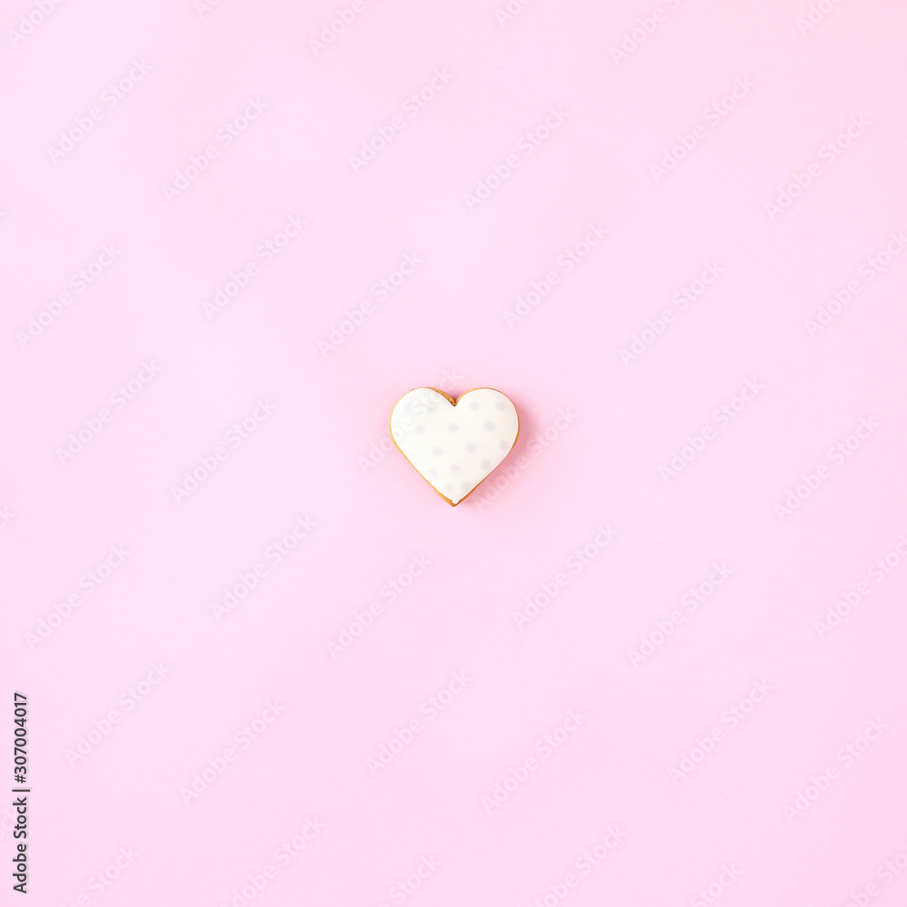 Heart shaped cookie on pink background.
