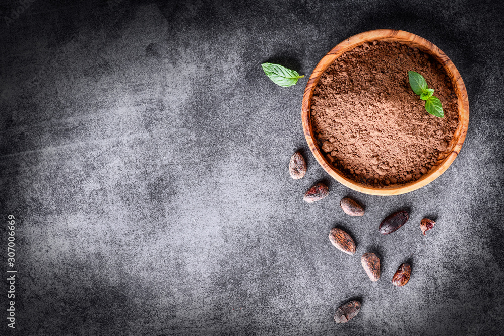 Cocoa beans and chocolate cacao powder with mint on top view. Copy space for text, dark stone table. Cocoa beans and chocolate cacao powder with mint on top view. Copy space for text, dark stone table.