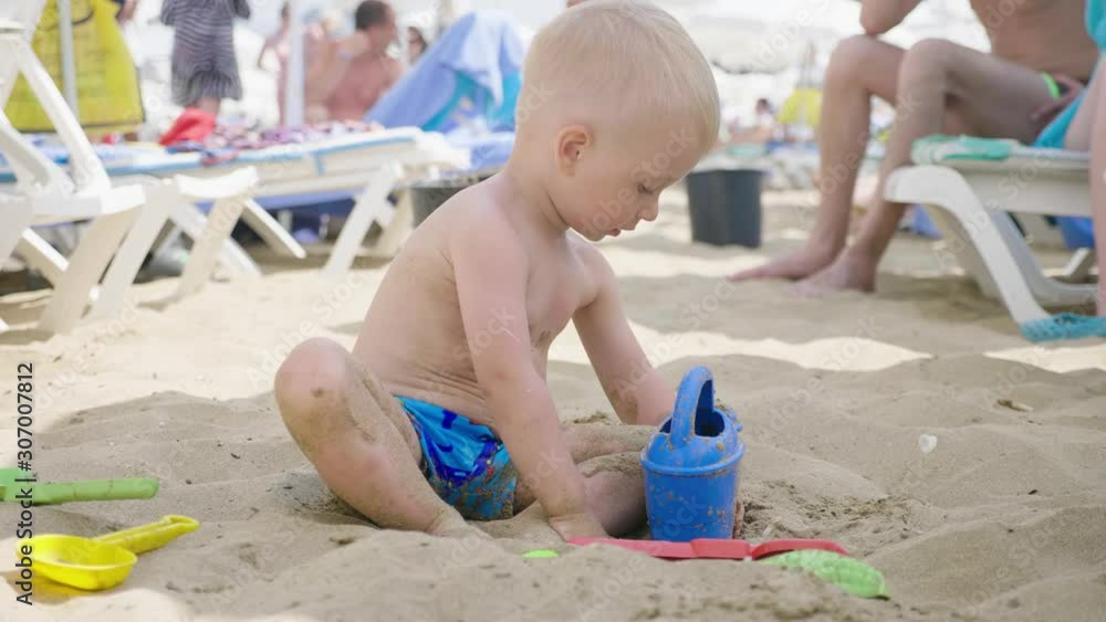 The cute little boy playing toys with sand at sea beach. Child os on vacation in summer at the beach on vacations. The cute little boy playing toys with sand at sea beach. Child os on vacation in summer at the beach on vacations.