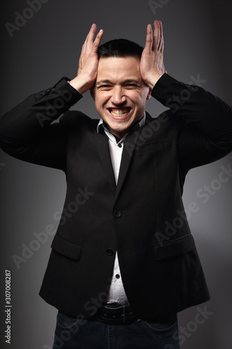 Angry business man in suit loud screaming with wide open mouth and gesturing the hands on grey background. Closeup
