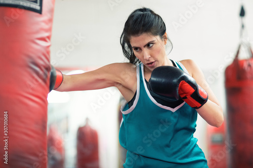 A young female boxer punching a bag in the gym © Llstock