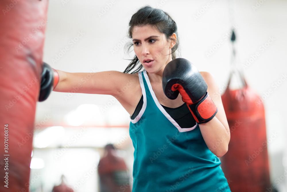 A young female boxer punching a bag in the gym A young female boxer punching a bag in the gym