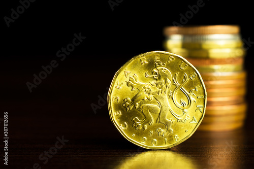 Businessman holds a yellow coin with his finger. Czech korunas on the table. Yellow coins on the table. Twenty Czech korunas. photo