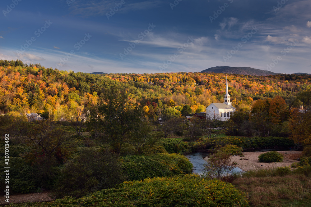 Obraz premium Stowe Community Church and Brush Hill with Fall colors in evening sun at Stowe Vermont