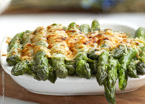 Front and close-up view of some asparagus gratin on a white fountain and unfocused background