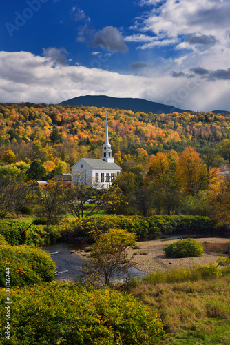 Stowe Community Church with Brush Hill in sunshine with Fall colors Vermont