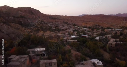 An aerial shot from a village in autumn leaves colorful trees forest and stair shape village town in mountain landscape in Iran