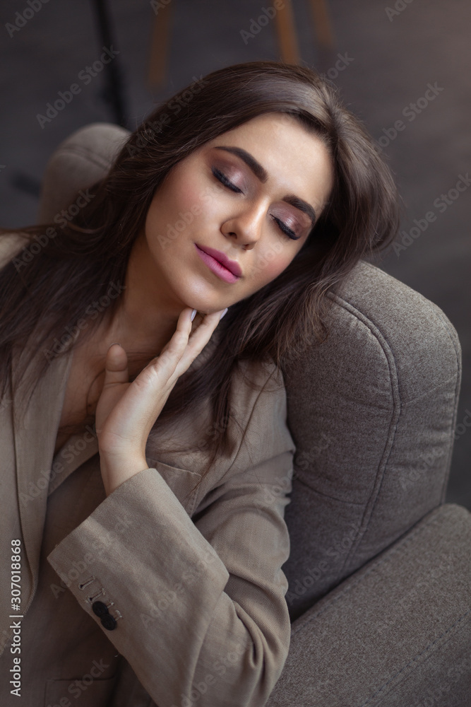 Sensual girl with closed eyes sits in a chair