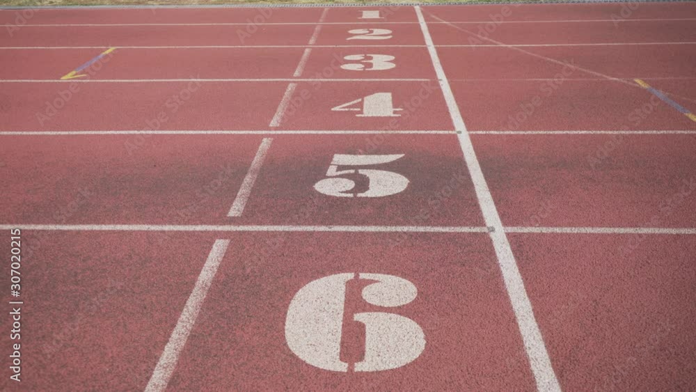 White markings on the red starting treadmill stadium seats with numbers. Low angle view of numbered lanes on a running track. No people. Start. The finish. White markings on the red starting treadmill stadium seats with numbers. Low angle view of numbered lanes on a running track. No people. Start. The finish.