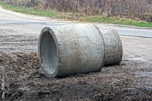 two gray concrete rings lie on the ground by the road