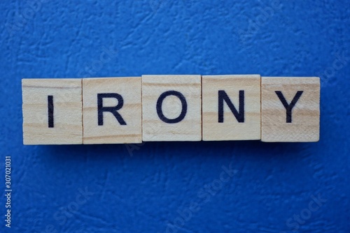 word irony made from wooden letters lies on a blue table photo