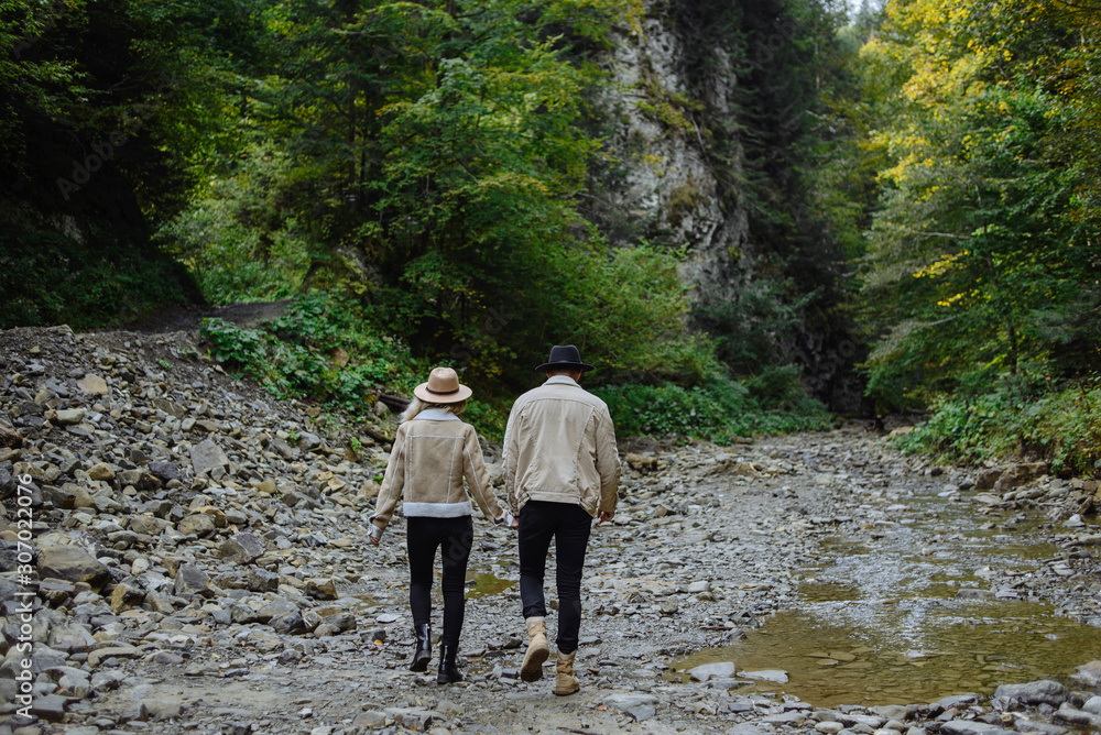 Two tourists go towards the forest and mountains Two tourists go towards the forest and mountains
