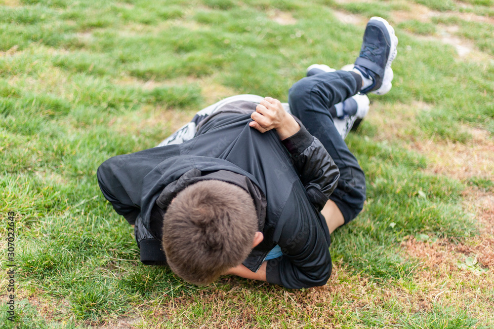Children fight. Conflict of teens on the playground. The guys are lying on the ground. Peers grappled in a fight. The child strikes a friend. Children did not share toys among themselves. Children fight. Conflict of teens on the playground. The guys are lying on the ground. Peers grappled in a fight. The child strikes a friend. Children did not share toys among themselves.