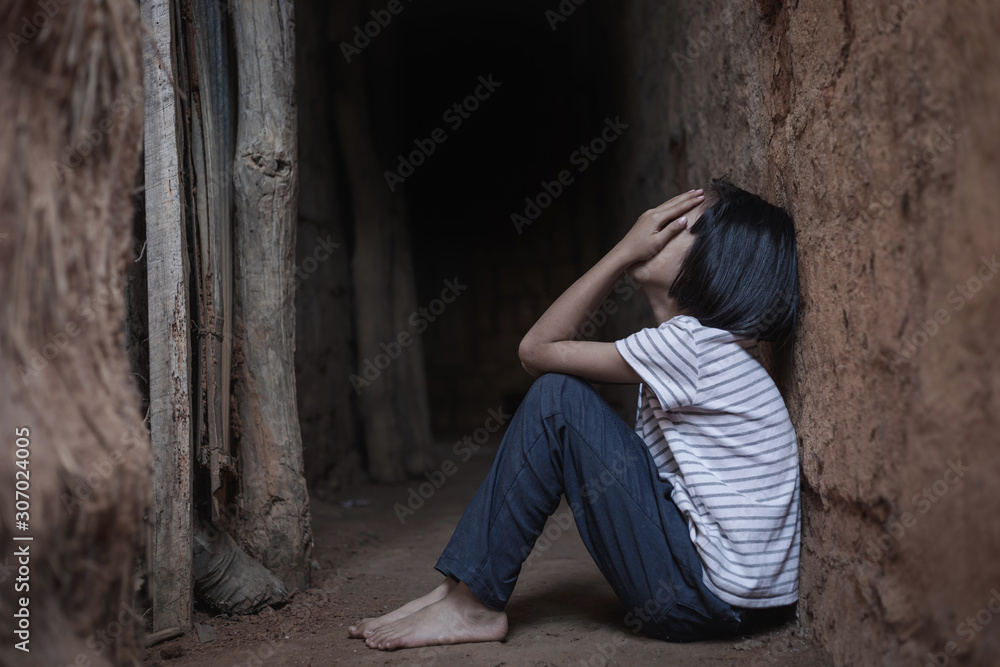 sad poor little child girl lean against the wall