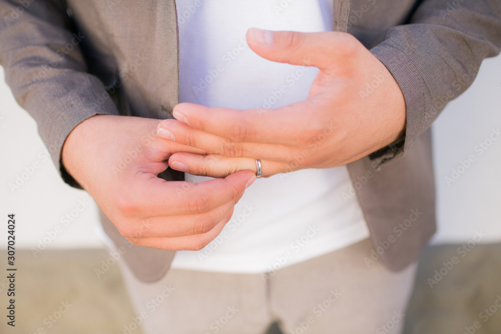 A man removes a wedding ring from a finger of his hand. Bad relationship with his wife. Divorce couples.