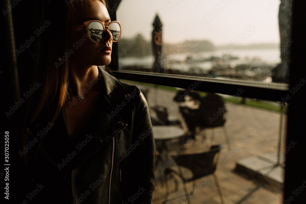 beautiful girl model in a restaurant in a beautiful loft interior. on the eyes of sunglasses, dressed in a leather black jacket, casual clothes. warm photography, sunlight beautiful girl model in a restaurant in a beautiful loft interior. on the eyes of sunglasses, dressed in a leather black jacket, casual clothes. warm photography, sunlight