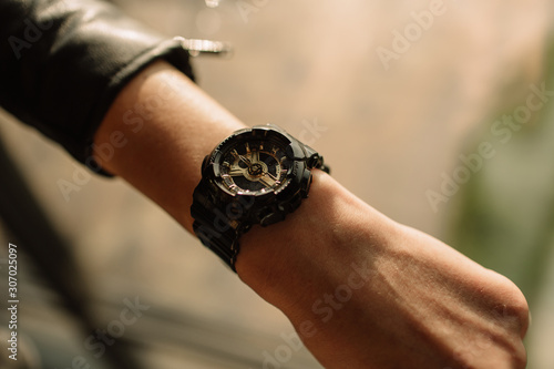 Black watch with golden arrows on a woman's hand. Fashion watches in a modern style