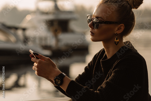 Young businesswoman working. Works on the phone, holds the phone in his hands, against the backdrop of a yacht, water.
