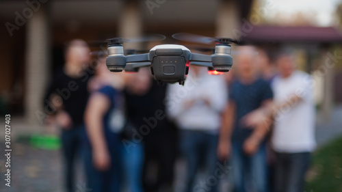 Flying drone, against the background of the company of young people. Unmanned aerial vehicles. Photos and videos from the drone.