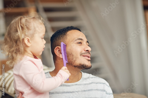 Portrait of cute little girl brushing dads beard while playing together at home, copy space