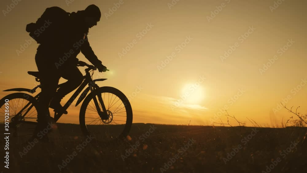 The silhouette of the mountain bicycle rider on the hill with bike at sunset. Sport, travel and active life concept. The silhouette of the mountain bicycle rider on the hill with bike at sunset. Sport, travel and active life concept.