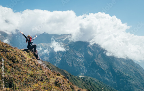 Young hiker backpacker female rising her arms,cheerful laughing and enjoying valley during high altitude Everest Base Camp (EBC) trekking route near Namche Bazaar,Nepal. Active vacations concept image