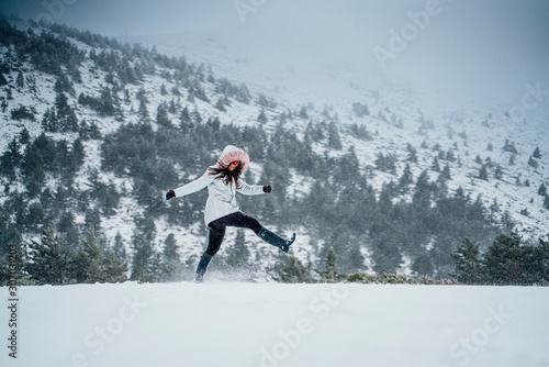 Attractive brunette woman walking through the snowy mountain