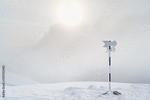 Blank hiking trail arrow/marker during a whiteout blizzard in the Carpathians (Baiului mountains), Romania, in Winter. photo