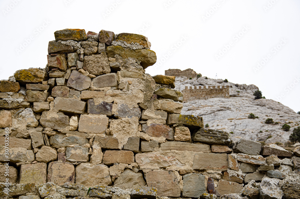Tower and wall of an old fortress in the mountains. Ruins and excavations. Tower and wall of an old fortress in the mountains. Ruins and excavations.