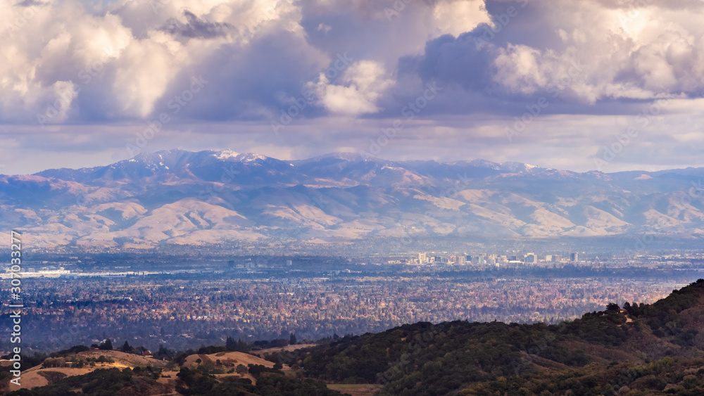 Aerial view San Jose, part of Silicon Valley; snow is visible on top of Mount Hamilton (part of Mount Diablo mountain range); storm clouds cover the sky; San Francisco Bay Area, California