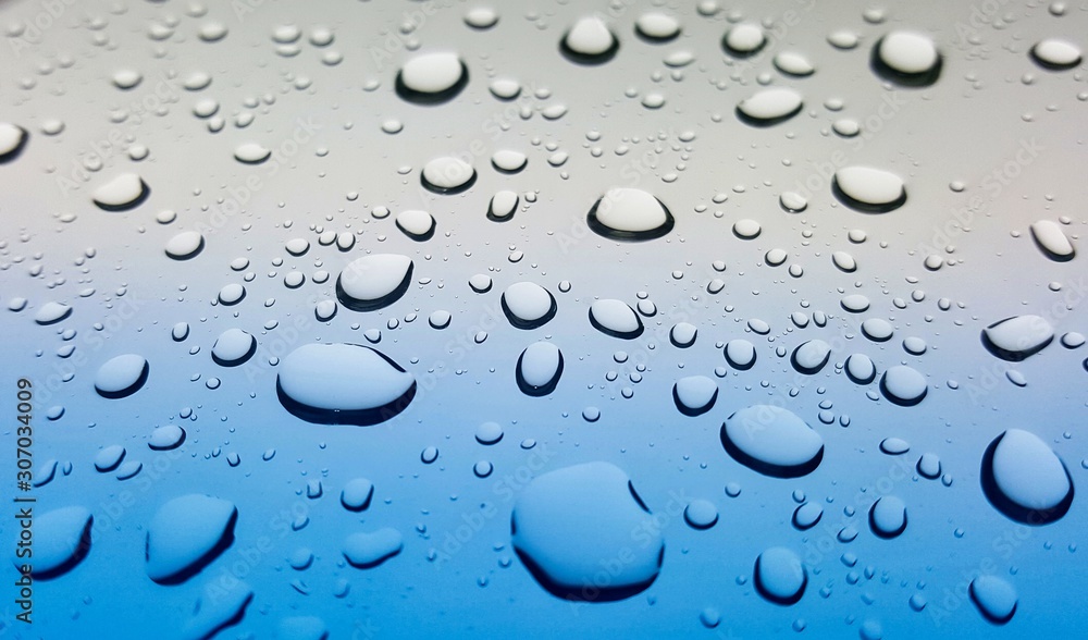 Splashes of raindrops on a car windshield after a storm. Angled point of view for depth of field and selective focus.