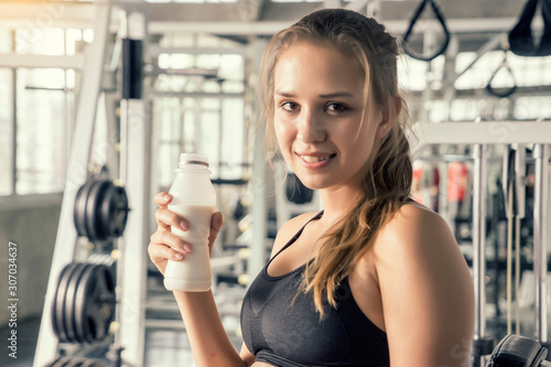 Asian women drink milk from bottles after exercise and support in gym Fitness, sport, health ,exercising and lifestyle concept