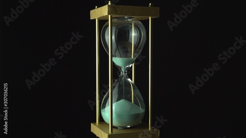 Hourglass clock time concept. Old vintage gold metal frame green sand clock countdown on dark background. Close up.