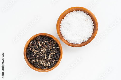 wooden bowls of salt and pepper on a white textured background